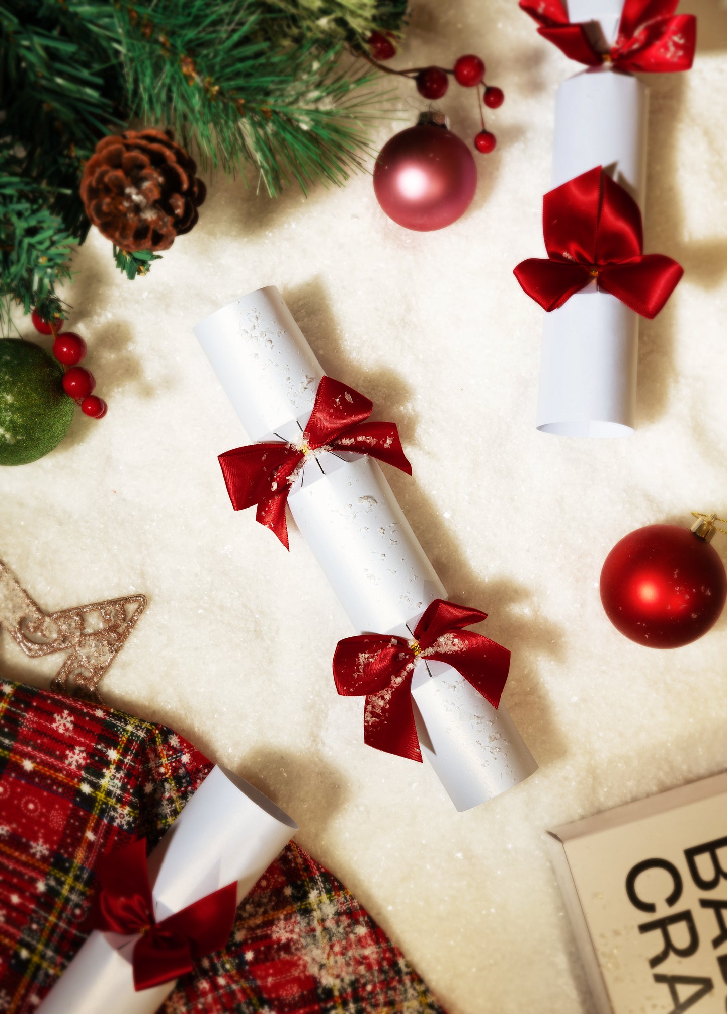 Decorative Christmas scene with Bad Crackers white with red bows, and festive decorations on snow.